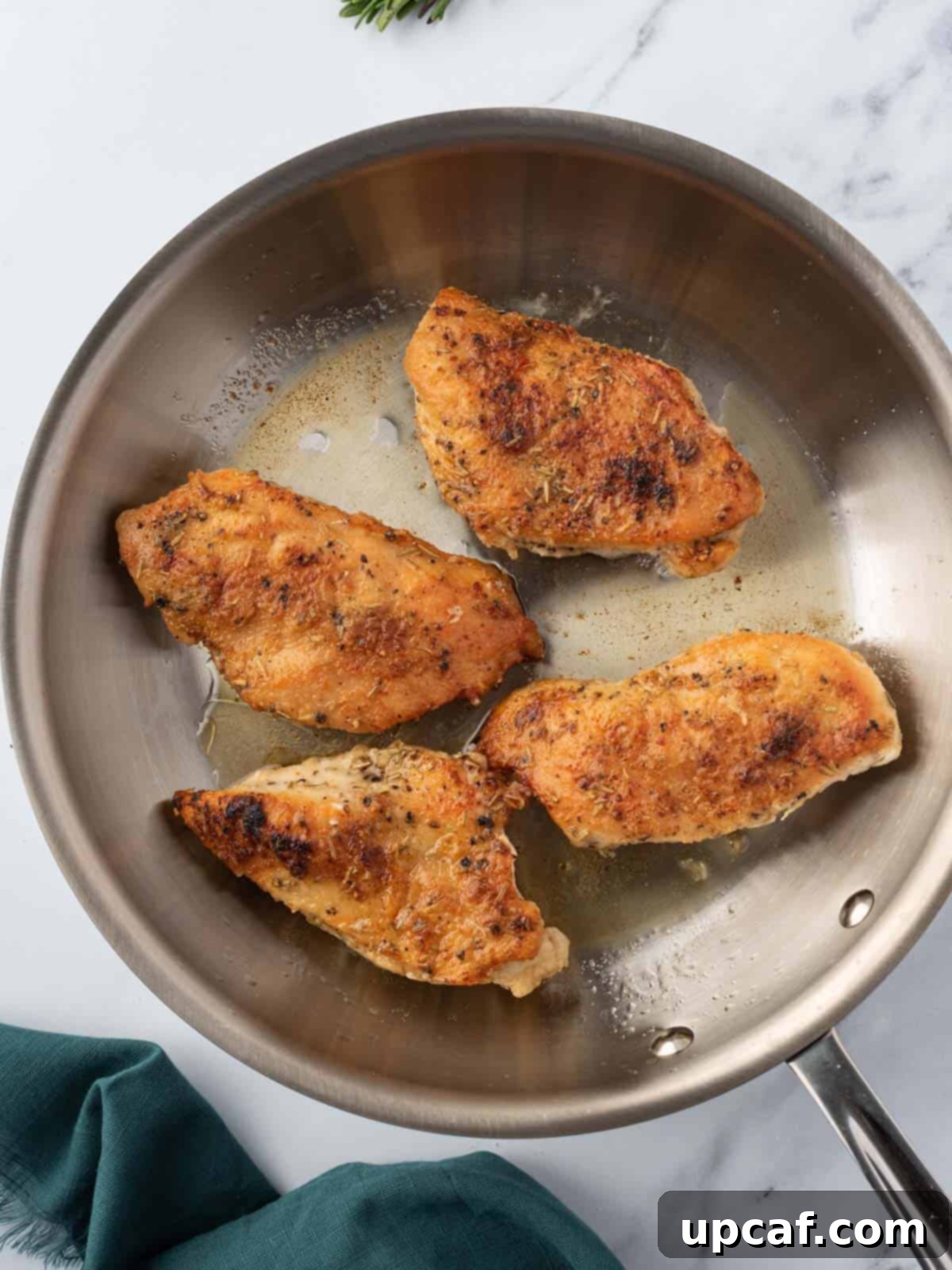 Chicken breasts searing in a hot skillet until golden brown.