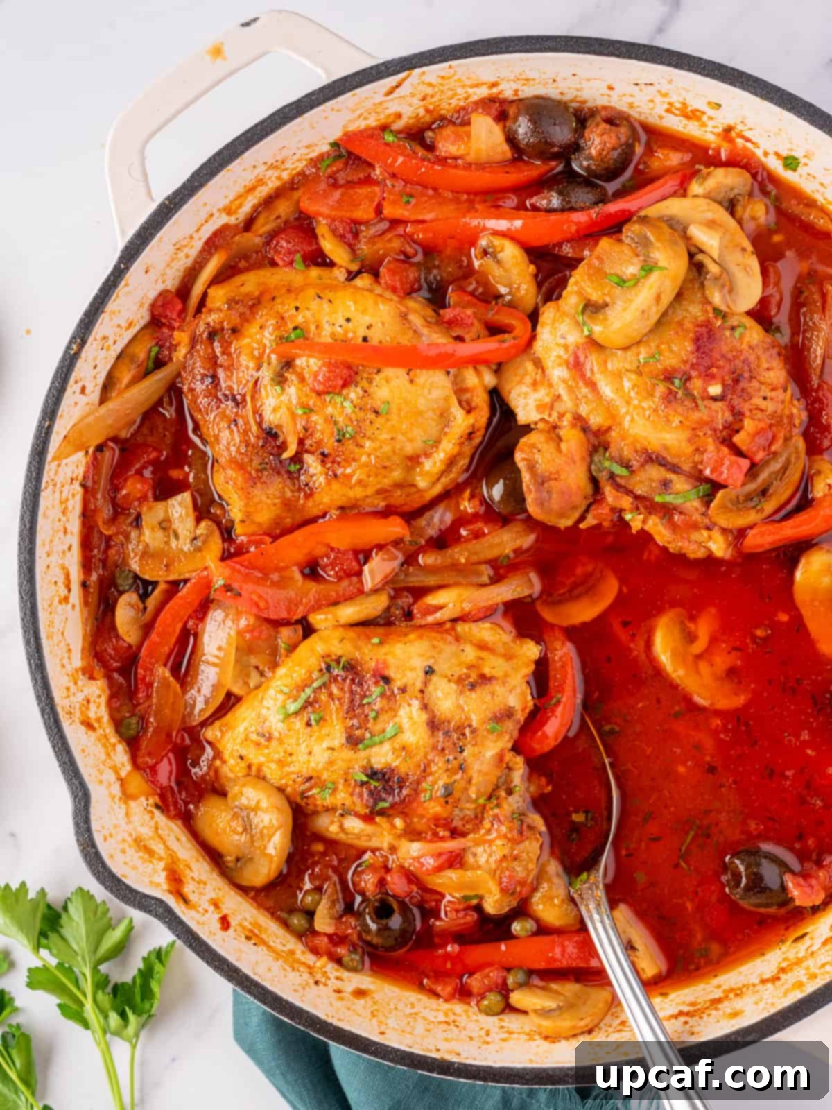 A full skillet of chicken cacciatore with one serving removed, showing its rustic appeal.