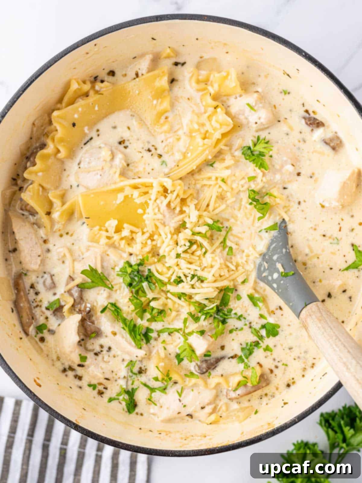 Creamy Chicken Lasagna Soup 8 A spoon stirring a pot of white lasagna soup, showcasing its rich and creamy texture.