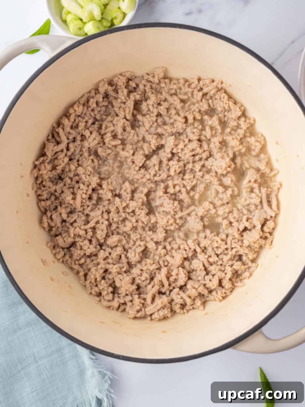 Browning ground chicken in a white dutch oven.