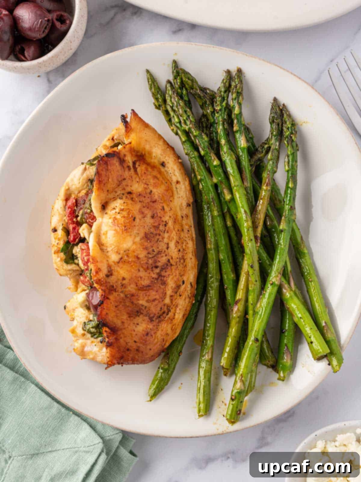 Sun-Drenched Mediterranean Stuffed Chicken 10 A plate of asparagus with Mediterranean stuffed chicken breast, ready to serve.