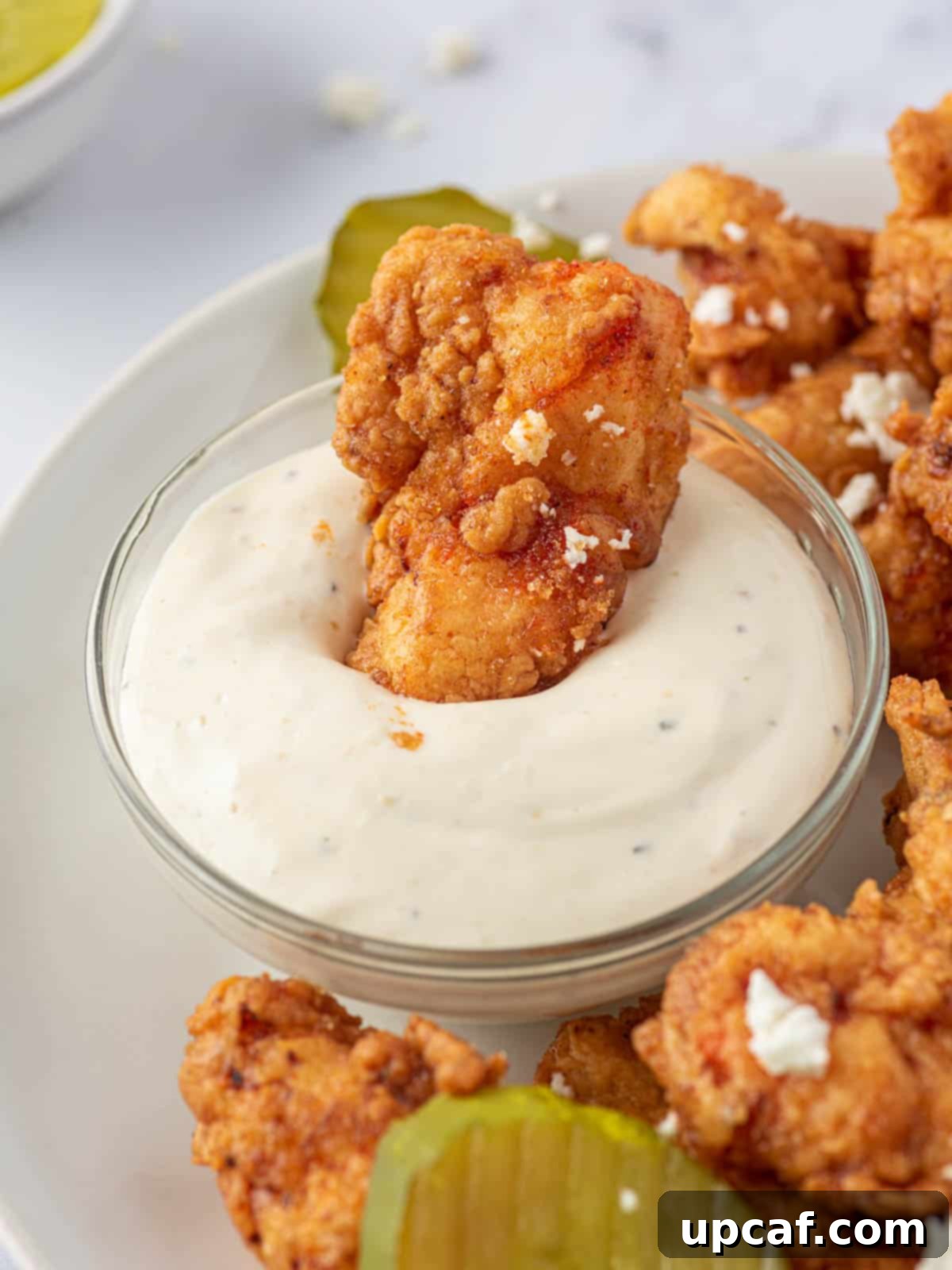 KFC's Fiery Nashville Chicken Tenders 10 A Nashville hot chicken tender being dipped into a creamy white sauce.