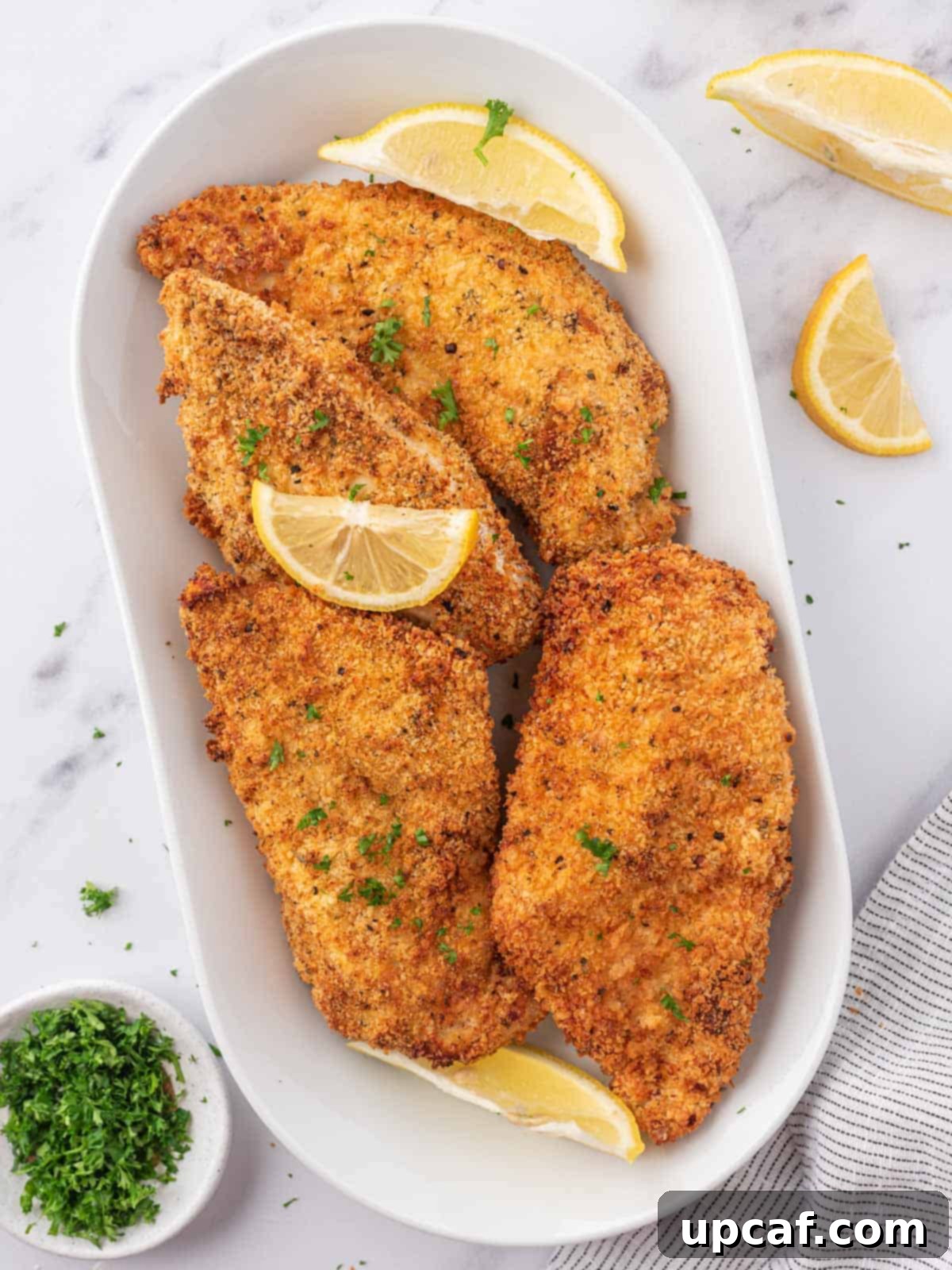 Crispy golden-brown chicken cutlets, freshly air-fried, garnished with fresh parsley.
