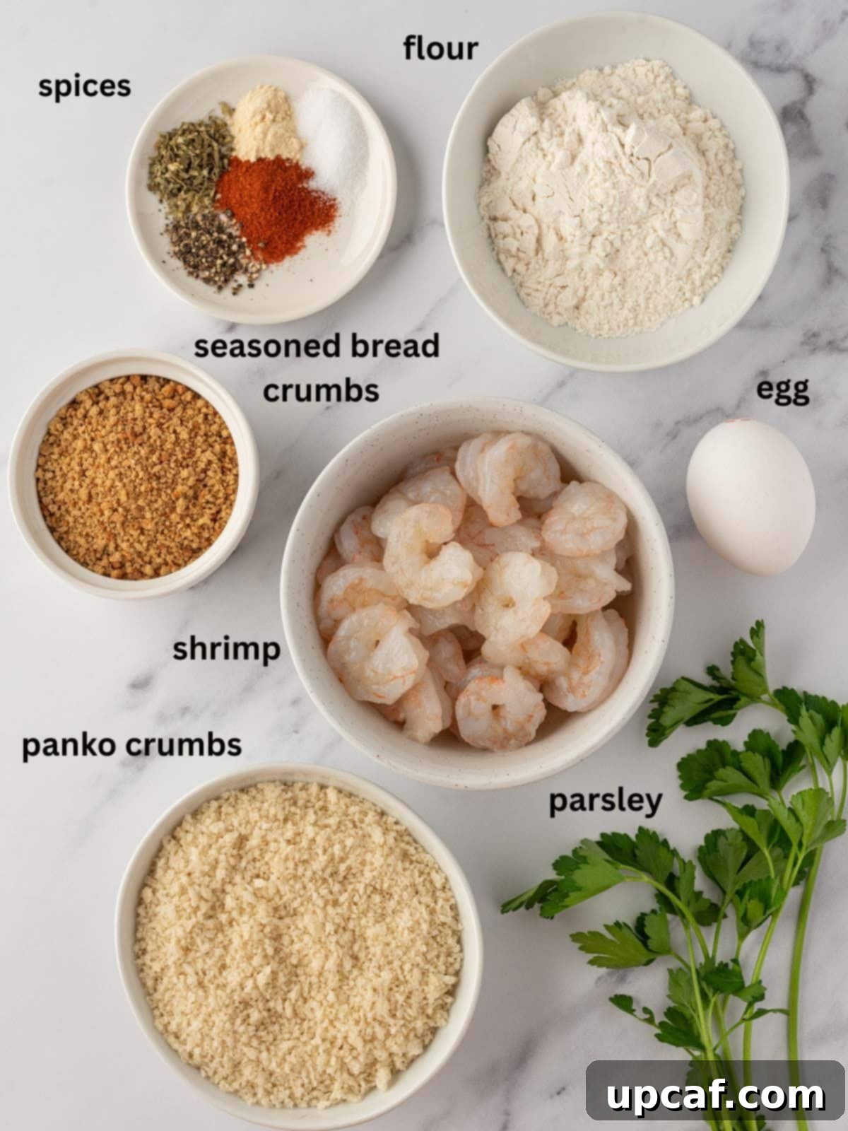 Ingredients needed for air fryer popcorn shrimp recipe, including fresh shrimp, flour, spices, egg, panko, and parsley.