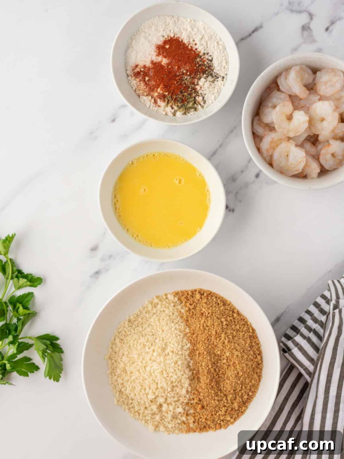 Three bowls showing the breading station for homemade popcorn shrimp: flour mixture, whisked egg, and breadcrumb mixture.
