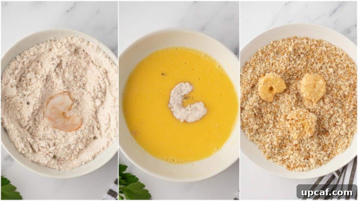 Close-up of shrimp being coated in flour, then egg, then breadcrumbs at a dredging station.