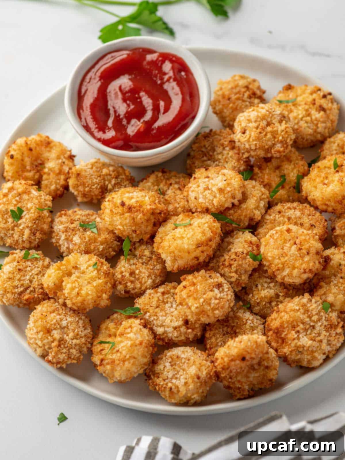 A white tray with air fryer popcorn shrimp and a small bowl of cocktail sauce, ready to be served.