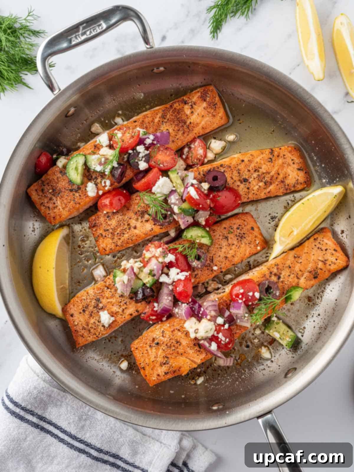 A skillet with perfectly cooked Greek salmon fillets topped with a fresh, colorful salsa.