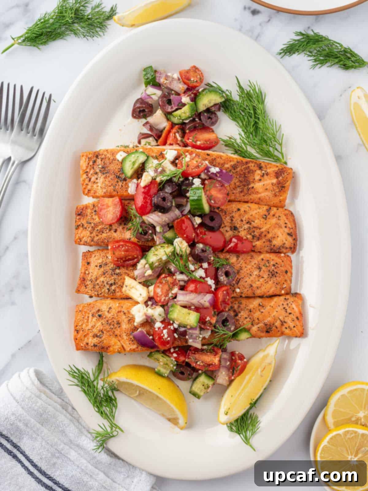 A beautifully plated Greek salmon recipe, served on a white dish and garnished with a generous spoonful of fresh Greek salsa.