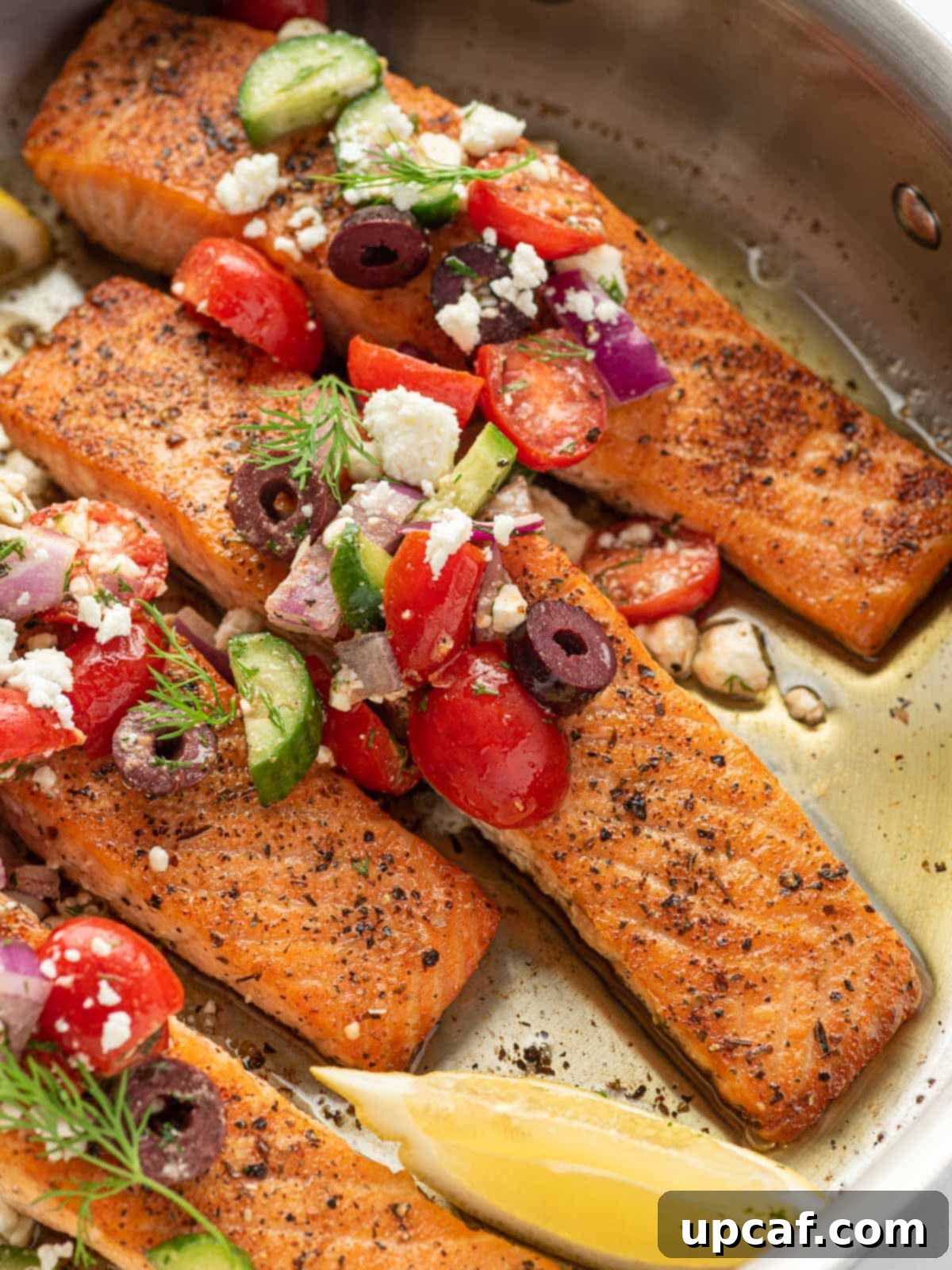 A close-up shot of a single Greek salmon fillet, glistening with pan-seared perfection, served in a skillet.