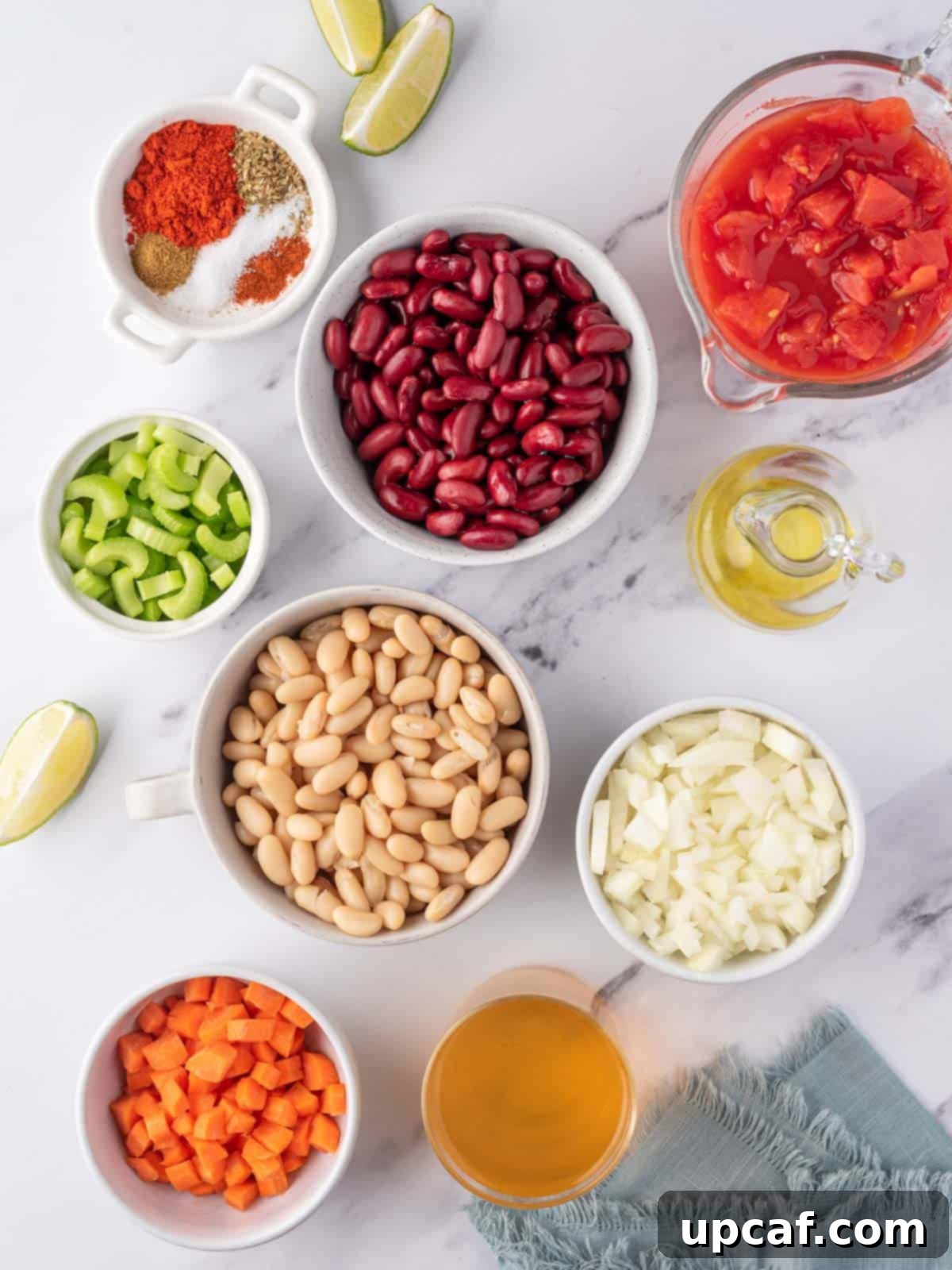 Bowls of meticulously prepped ingredients needed for easy vegan chili, including chopped vegetables, canned beans, and a selection of vibrant spices.