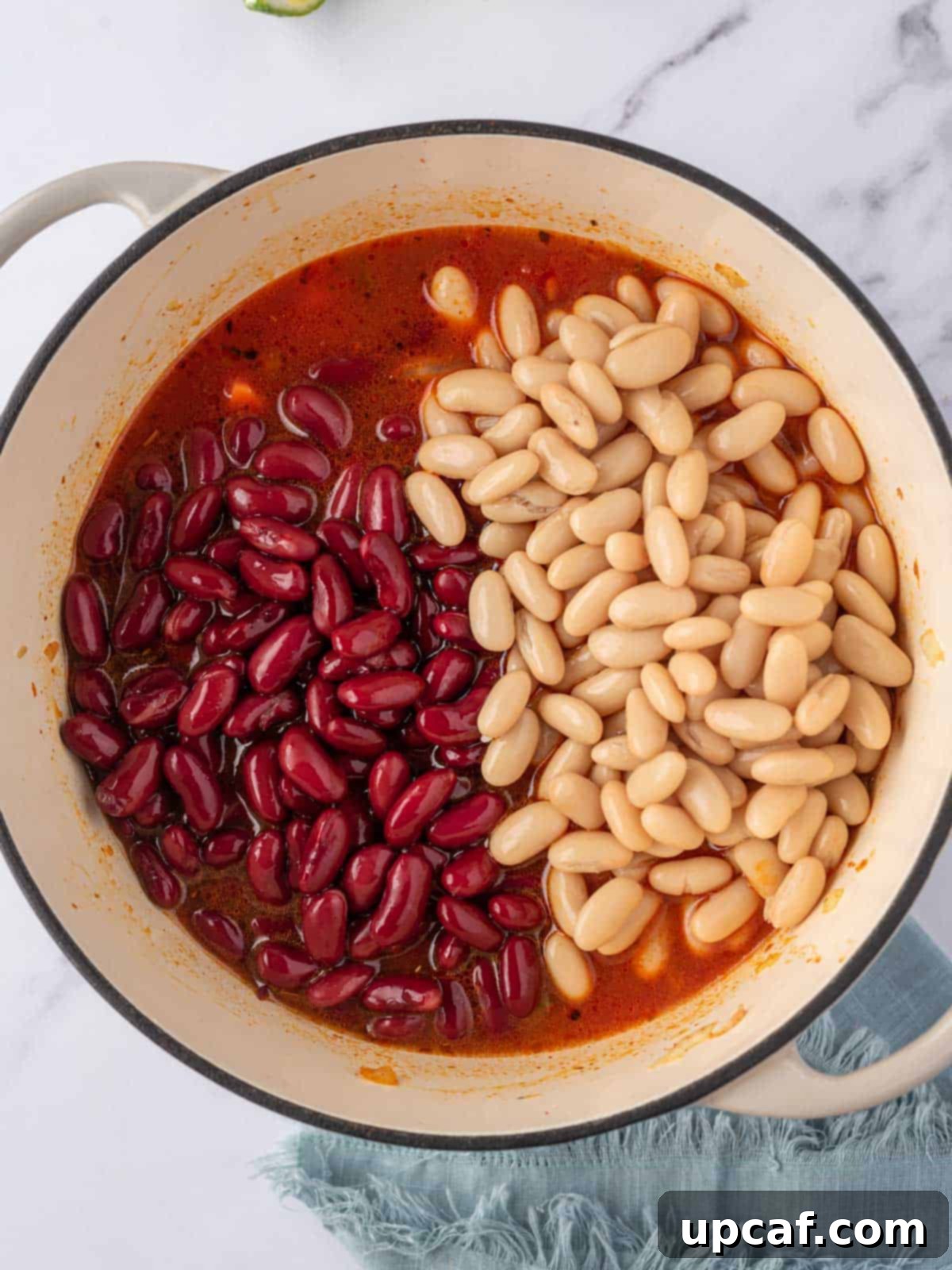 A visual of both white cannellini beans and red kidney beans, carefully separated and ready to be added to the rich, simmering vegan bean chili.