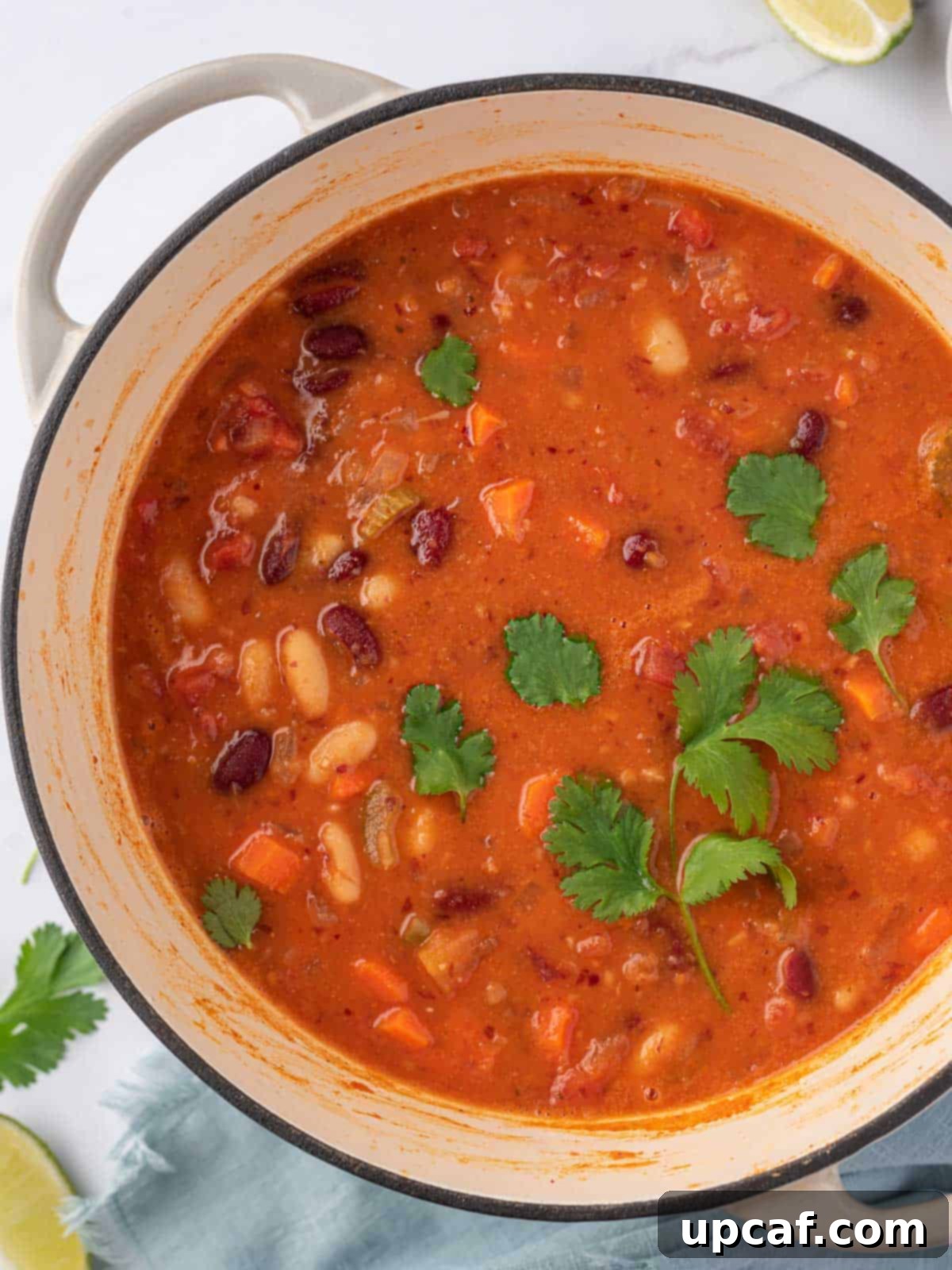 A large, rustic pot of steaming stovetop chili, generously topped with vibrant fresh cilantro, signifying its readiness to be enjoyed.
