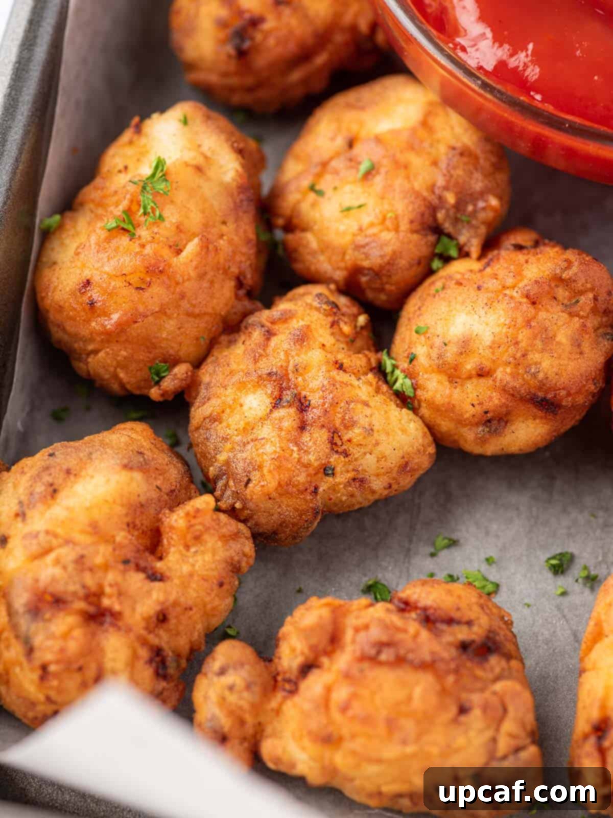 A close-up shot of several pieces of golden, crispy fried popcorn chicken arranged neatly on a serving tray, highlighting their texture.