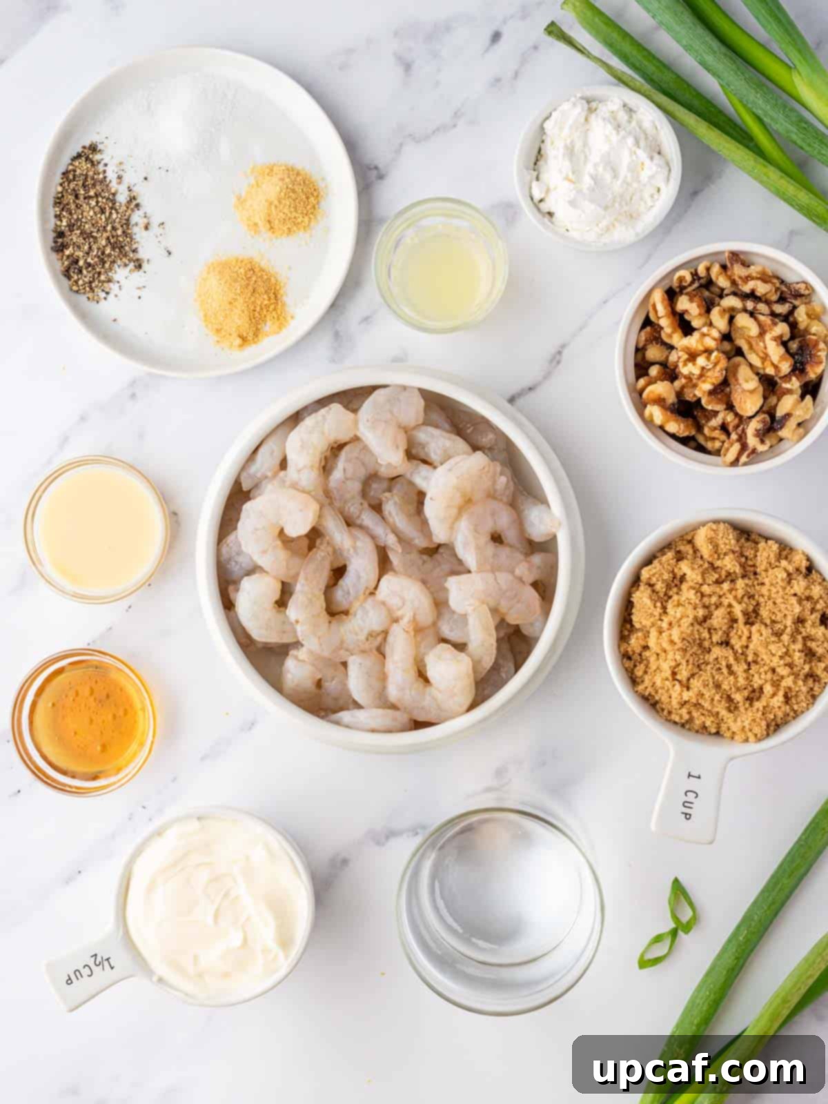A collection of fresh ingredients laid out on a table, including raw shrimp, walnuts, brown sugar, mayonnaise, condensed milk, honey, lemon, and seasonings, ready for making honey walnut shrimp.