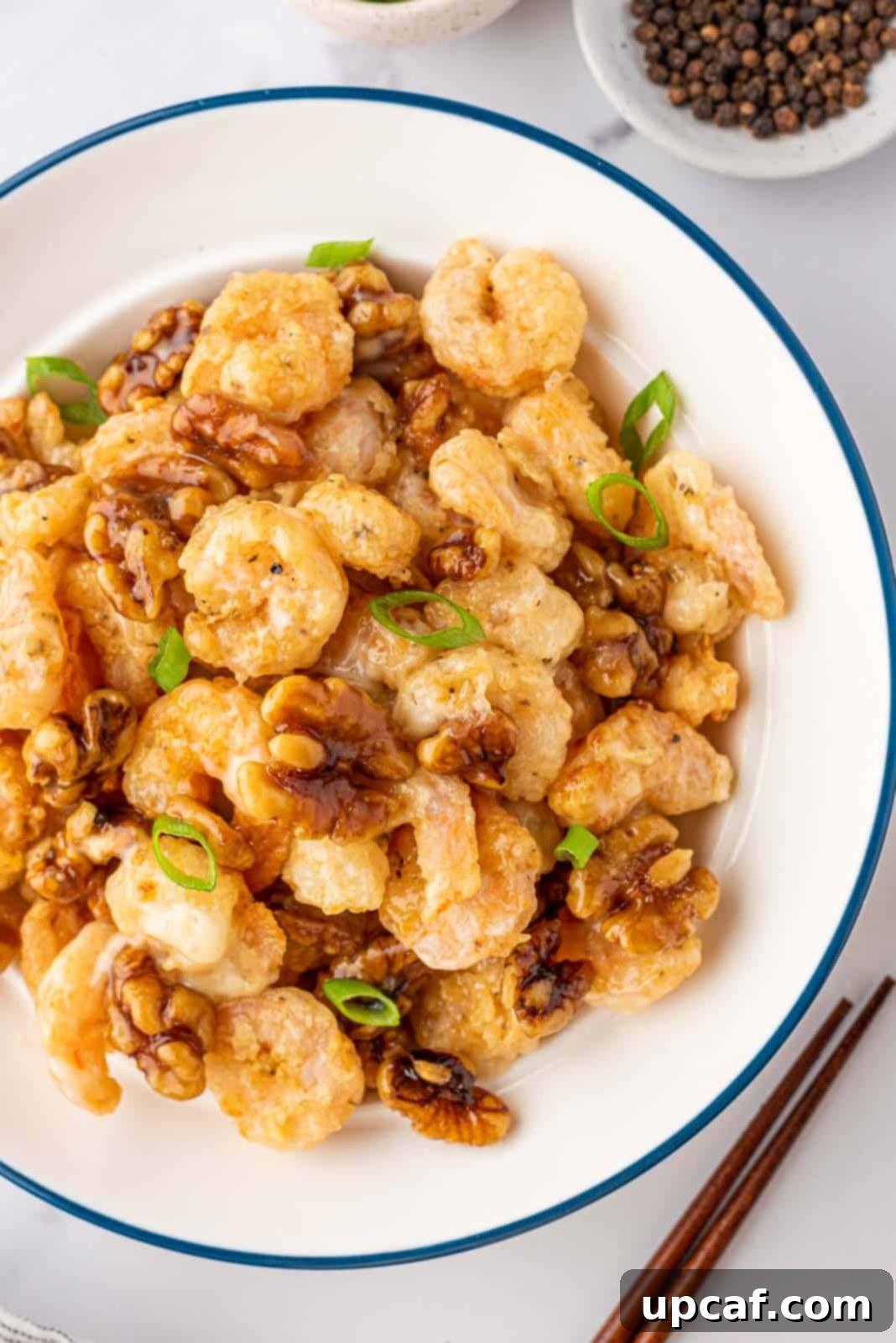 A full bowl of freshly prepared honey walnut shrimp, garnished with green onions, ready to be enjoyed.
