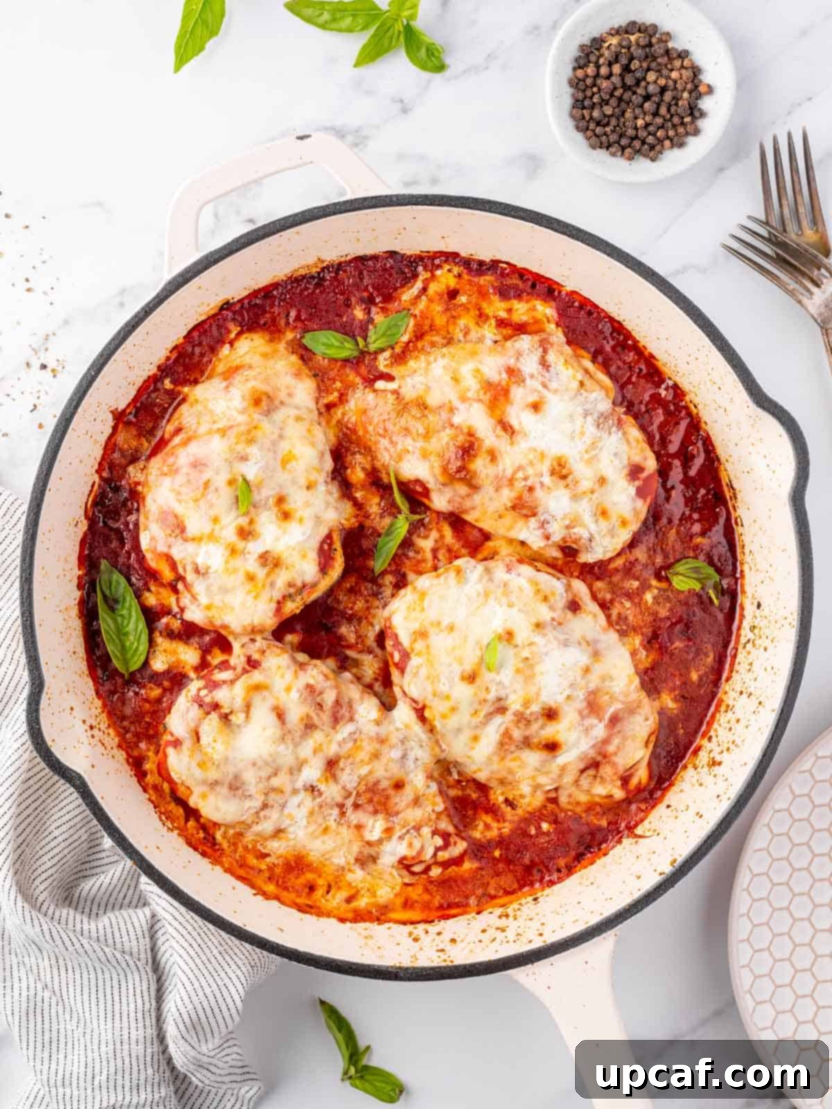 Keto Chicken Parm Skillet 2 Overhead view of a pan with golden-brown chicken parmesan, topped with melted cheese and fresh basil.