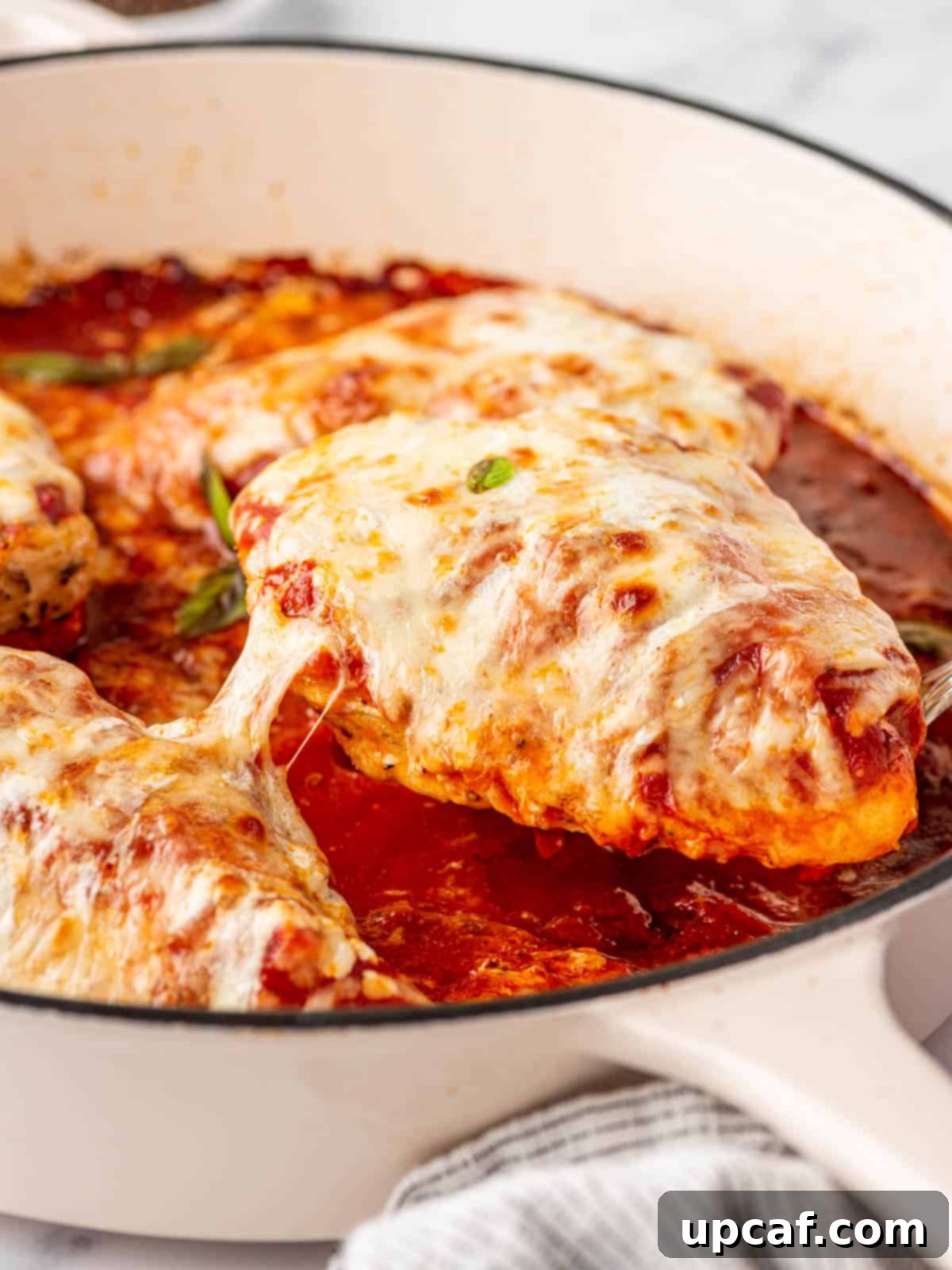 Keto Chicken Parm Skillet 8 A serving of low carb chicken parmesan being lifted from the skillet, showing the melted cheese and tender chicken.