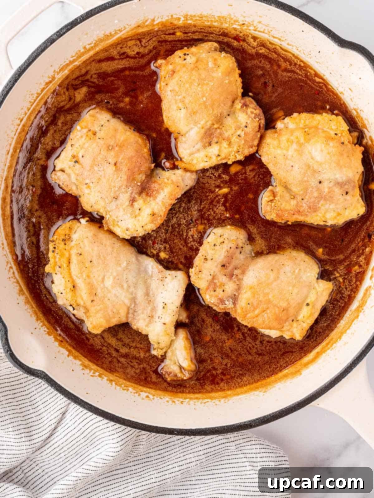 Chicken added to a pan of honey garlic sauce.