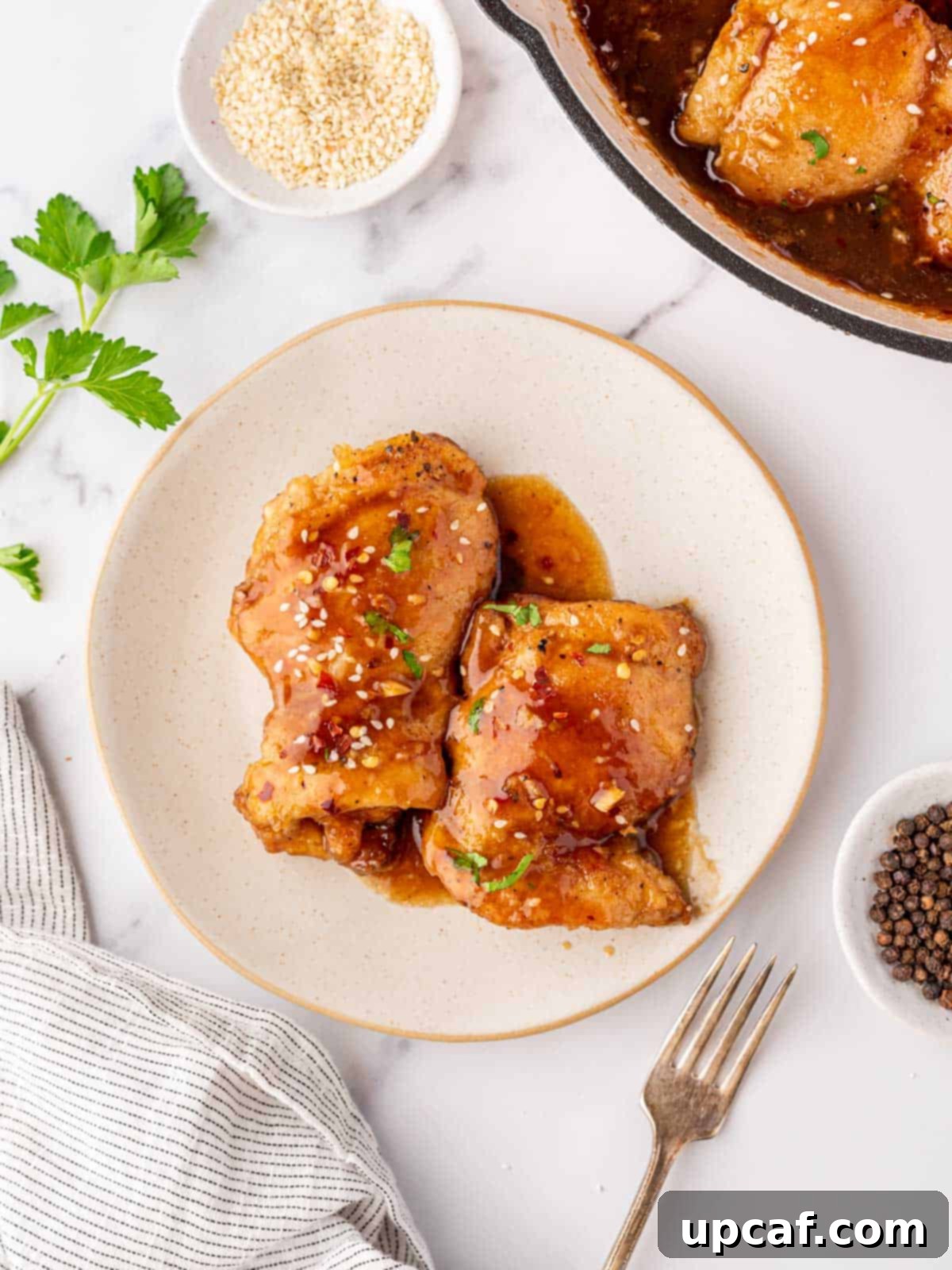 A plate with two honey garlic chicken thighs.