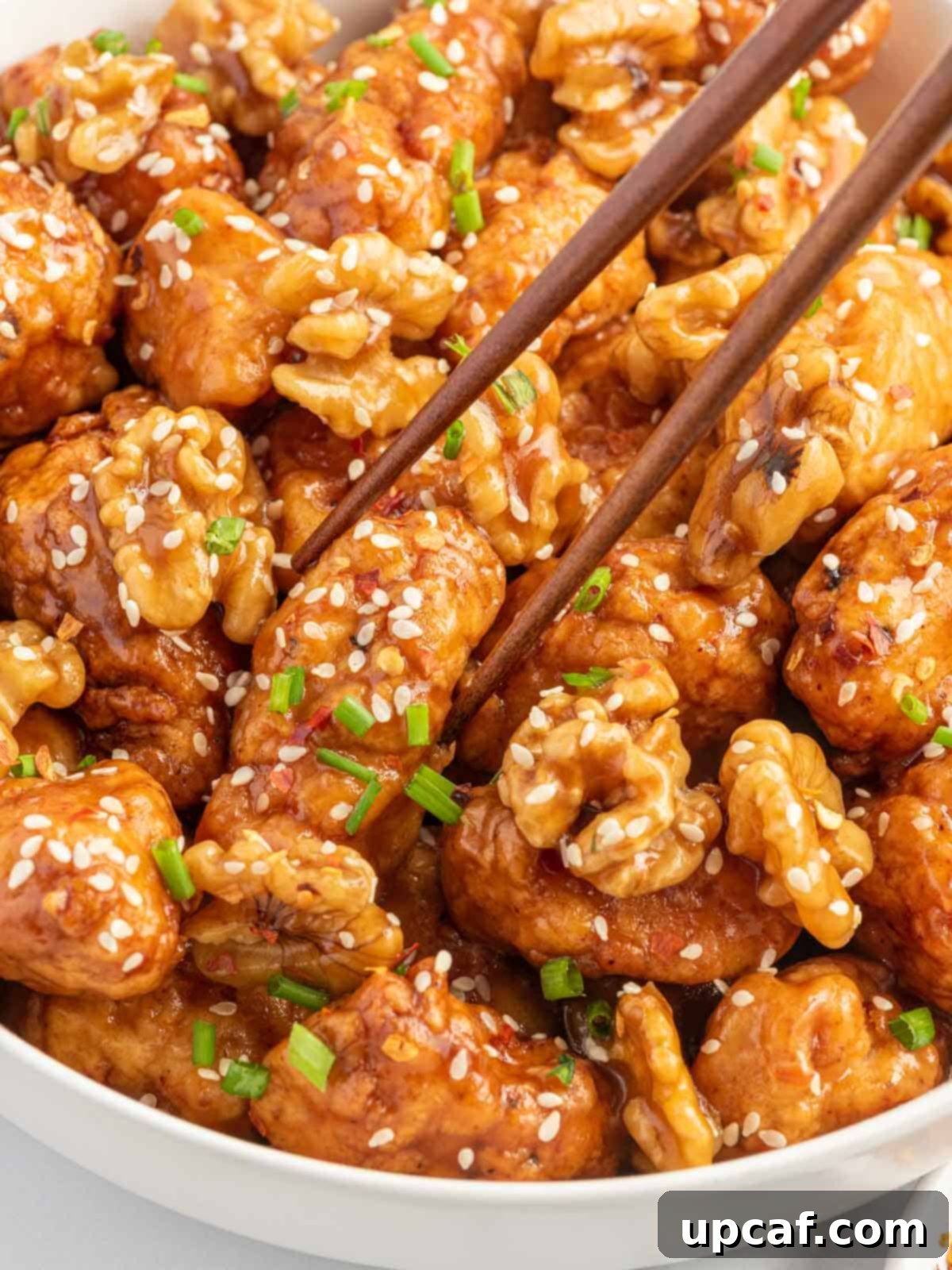 Caramelized Honey Walnut Chicken 8 chop sticks lifting a piece of chicken.
