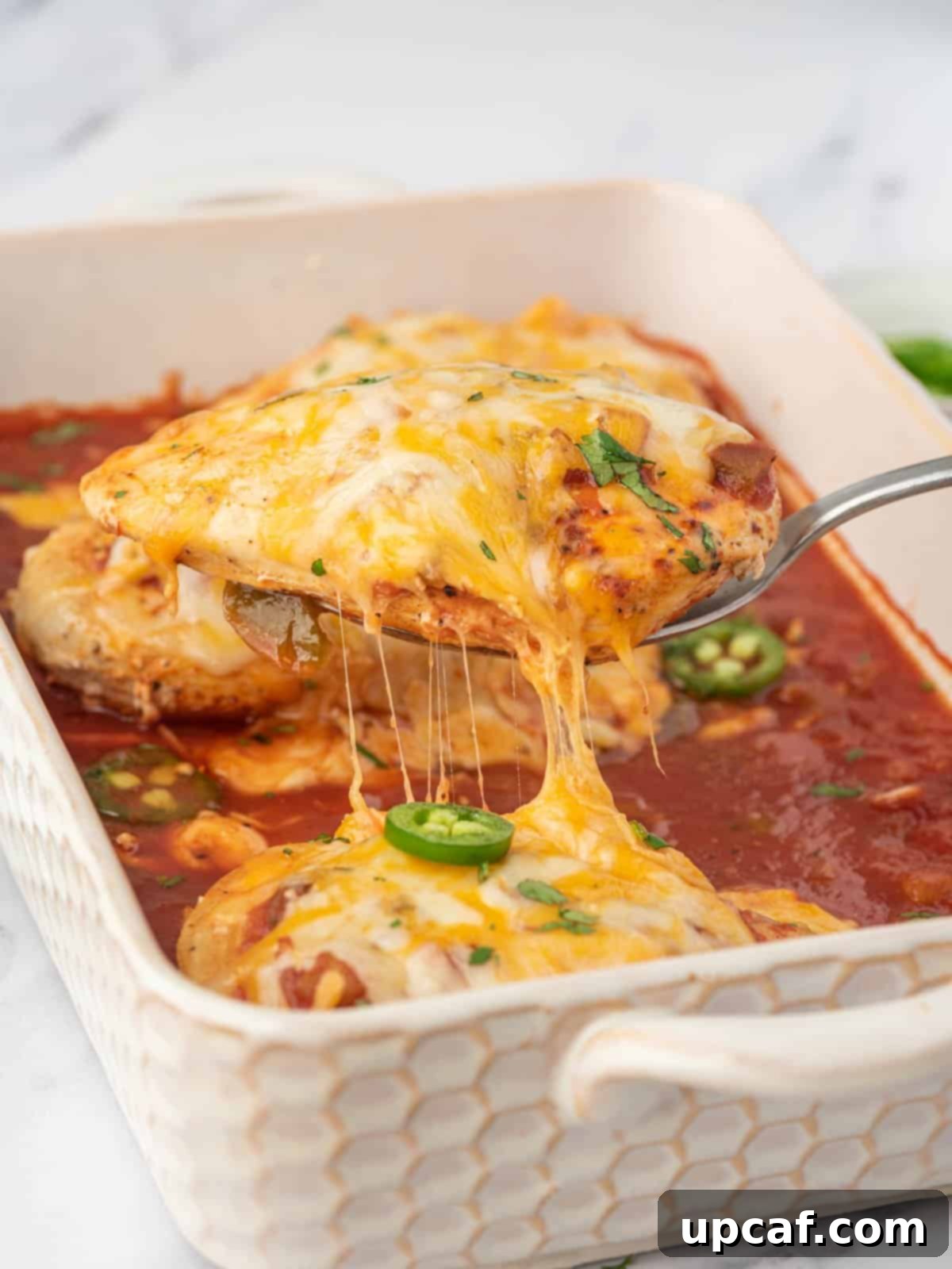 A serving of baked salsa chicken being lifted from the baking dish, showing the cheesy, saucy goodness.