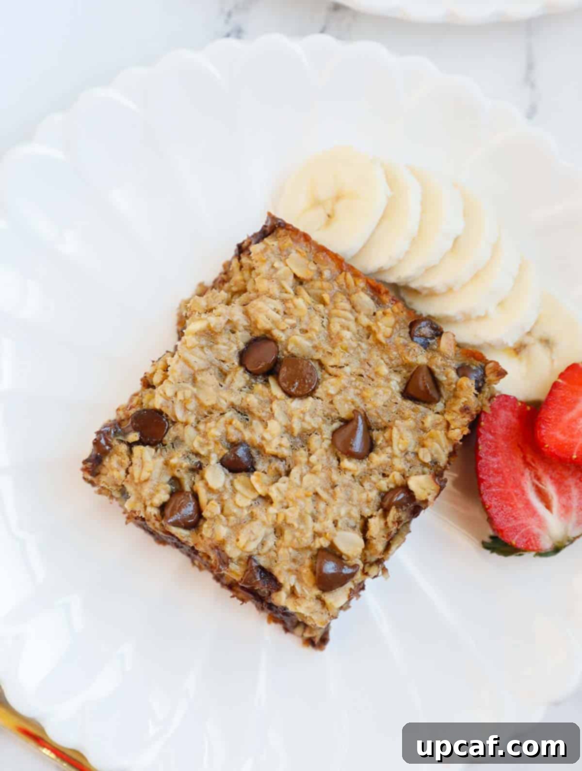 A slice of Chocolate Chip Baked Oatmeal on a white plate, garnished with fresh berries and a fork, ready to be enjoyed as a healthy breakfast.