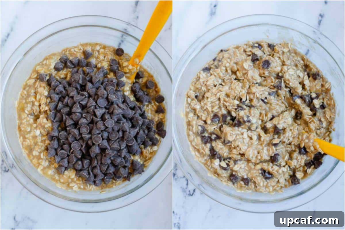 Adding a generous amount of semi-sweet chocolate chips to the prepared baked oats batter in a mixing bowl.