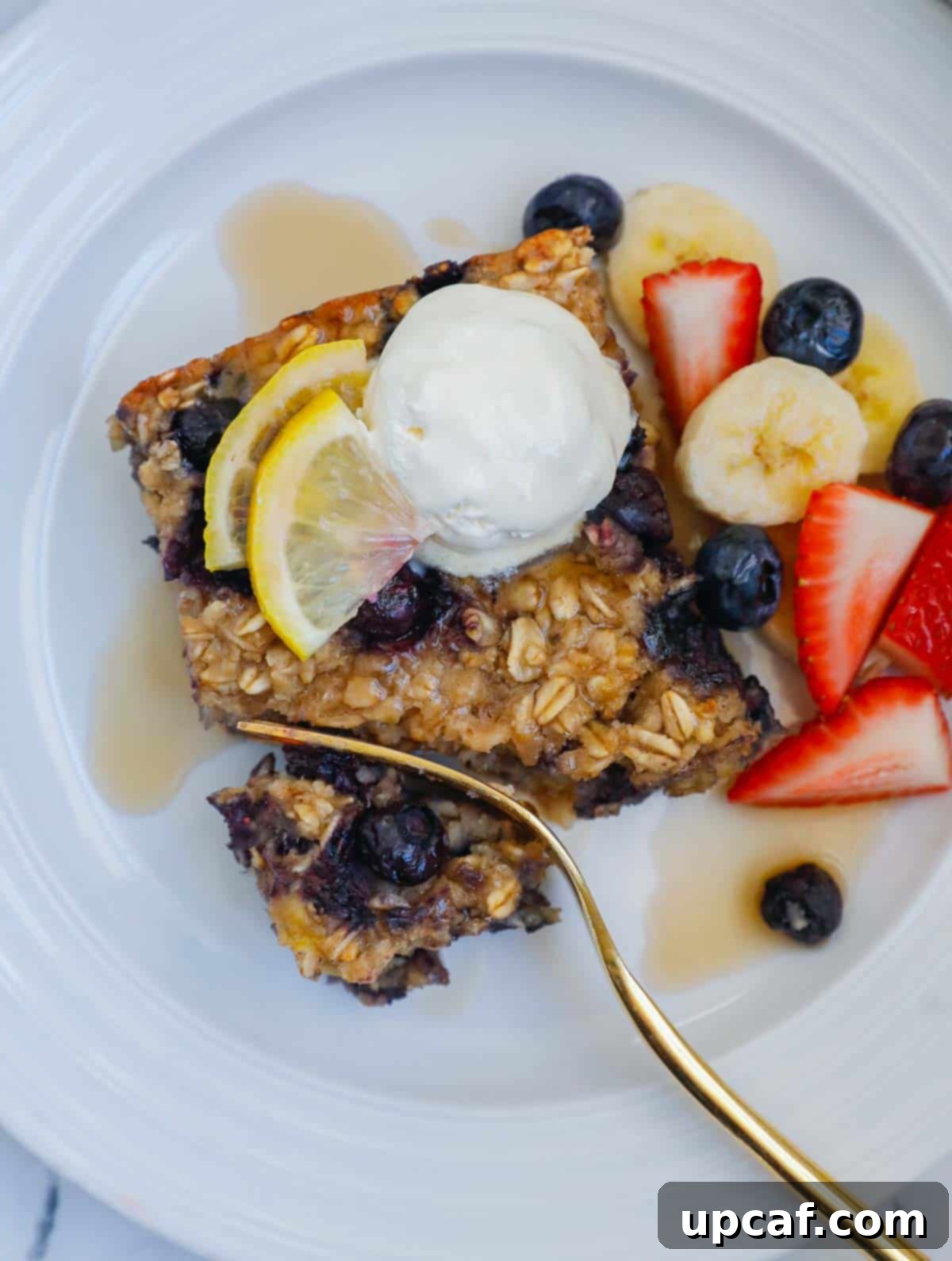Hearty Blueberry Baked Oatmeal 2 A fork cutting through a perfectly baked square of blueberry oatmeal bake, showing its tender interior and golden-brown top, garnished with fresh blueberries and a dollop of whipped cream.