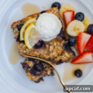 Hearty Blueberry Baked Oatmeal 9 A square of blueberry oatmeal bake on a plate topped with whipped cream and fresh fruit.