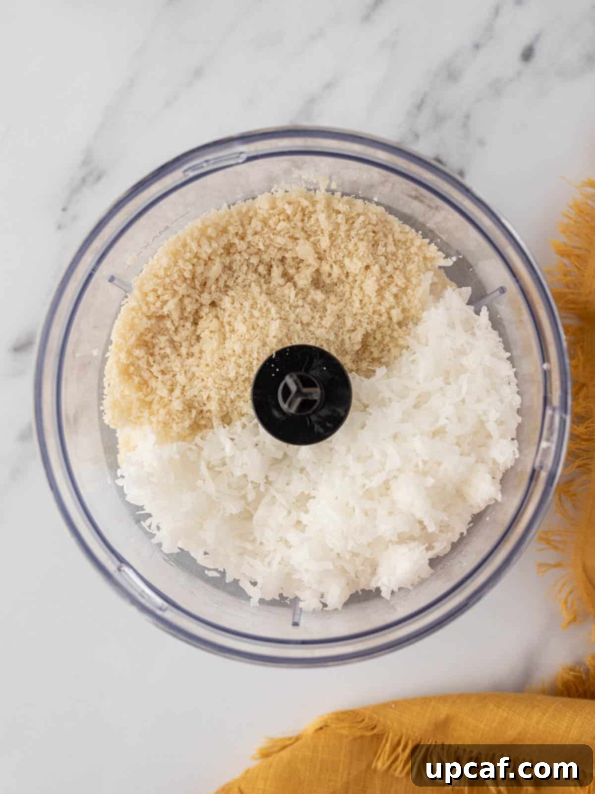 A close-up view of pulsed coconut flakes and panko bread crumbs, a perfectly textured mixture for air fryer coconut shrimp breading.