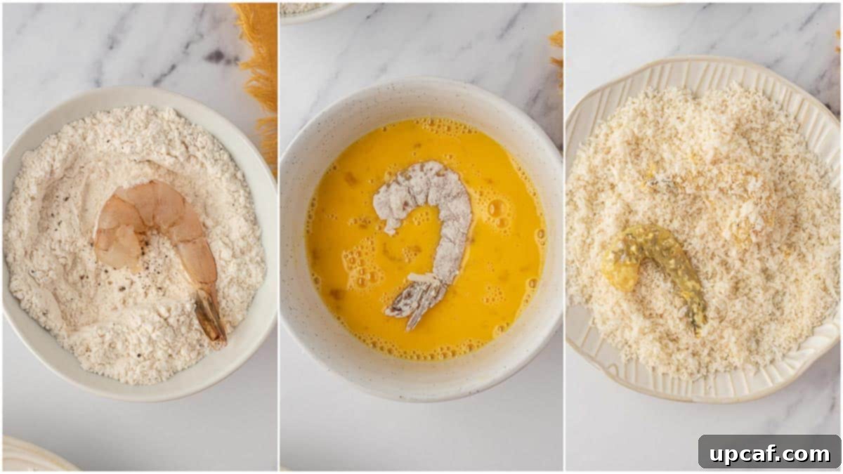 A hand dipping a shrimp into the flour mixture, illustrating the initial step of dredging for crispy air fryer fried shrimp.