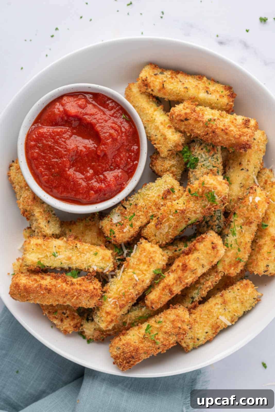 A large platter filled with golden, crispy air fryer zucchini sticks, ready to be served.