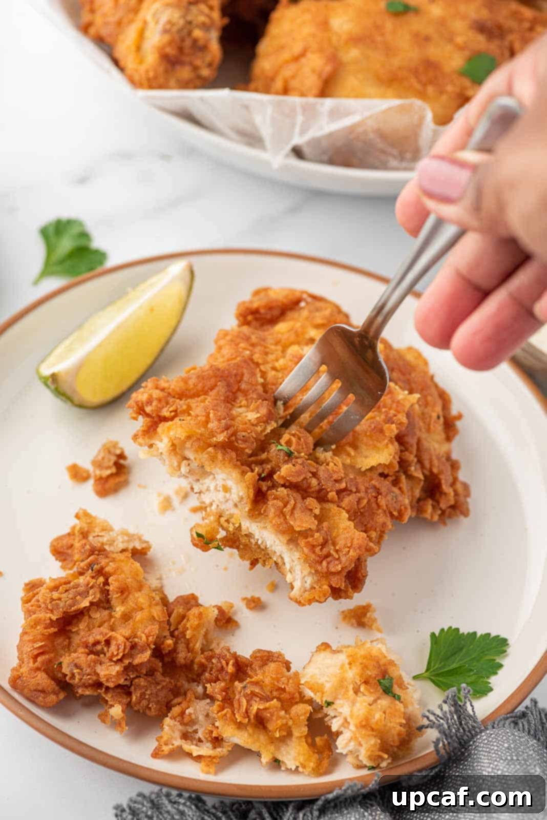Crispy Fried Chicken Perfection 9 A fork holds a piece of crunchy fried chicken.