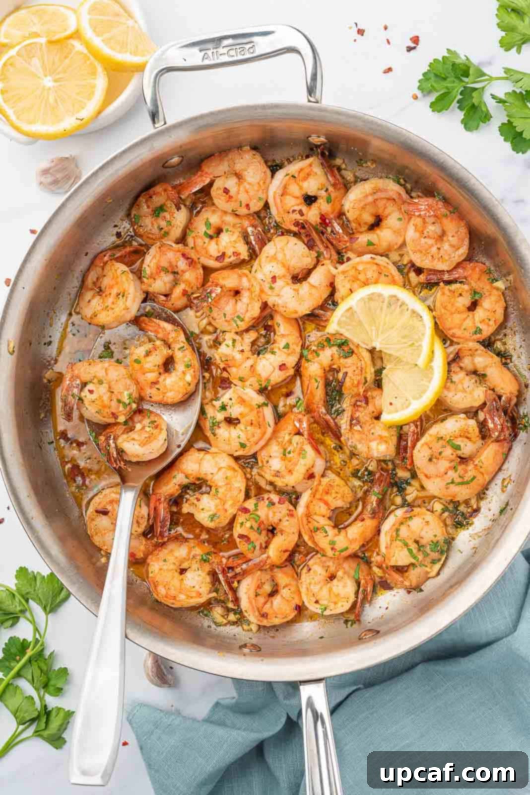 A skillet of golden-brown garlic and lemon shrimp, garnished with fresh parsley.