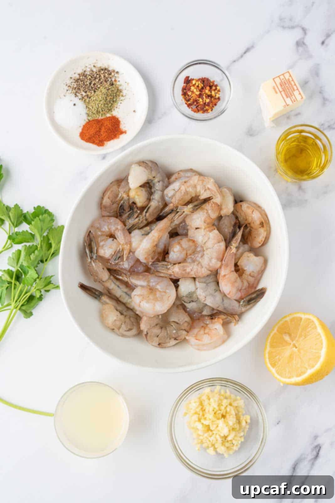 Fresh ingredients laid out for making lemon garlic butter shrimp: shrimp, garlic, lemon, butter, parsley, and seasonings.