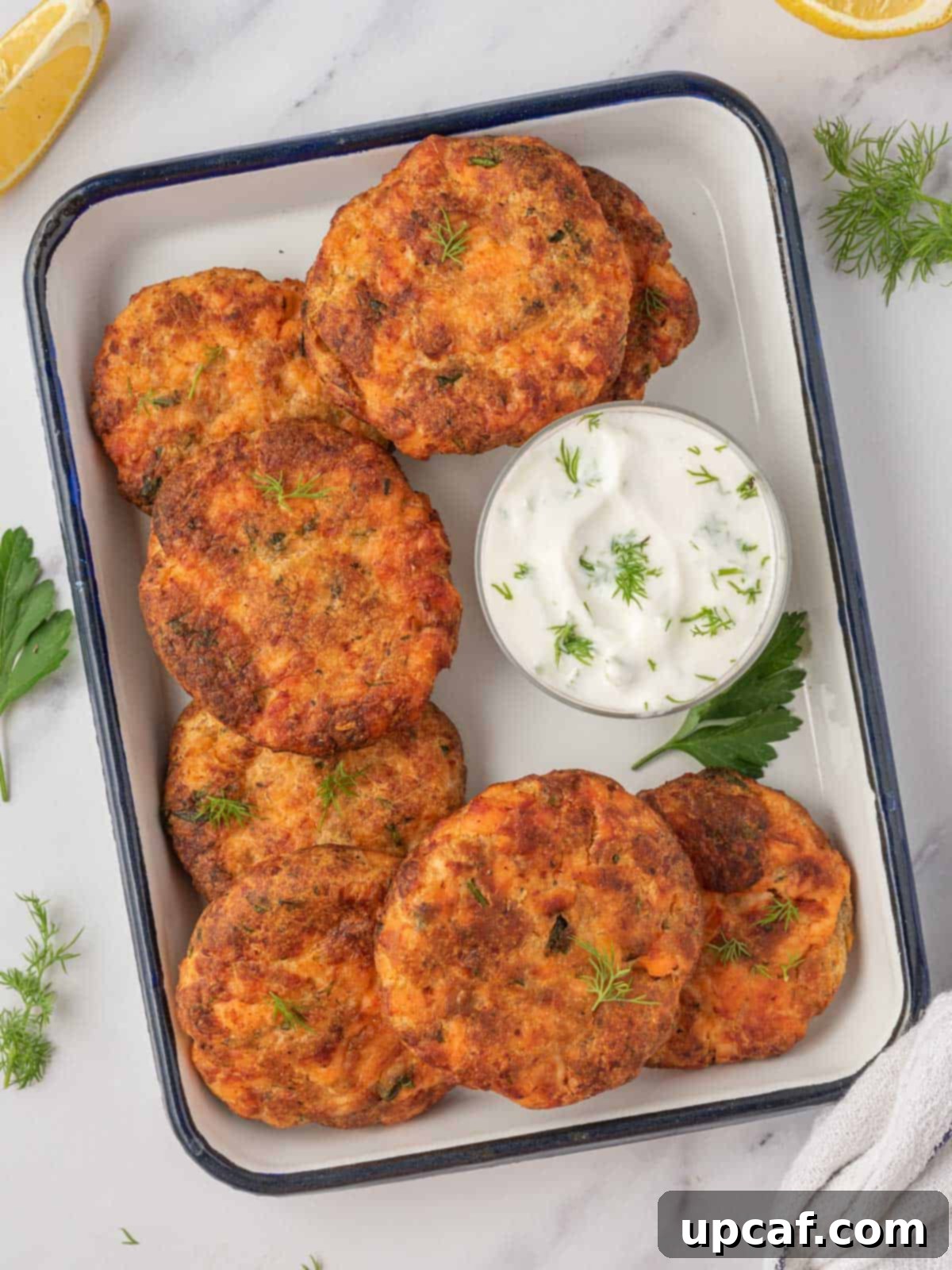 A tray of salmon croquettes air fryer with a small bowl of tzatziki sauce.
