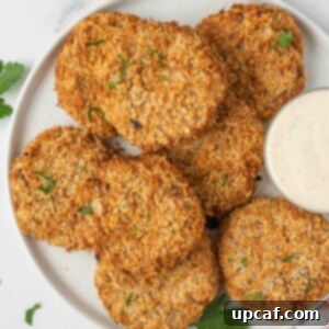 A plate with golden-brown crispy tuna cakes and a small bowl of dipping sauce, ready for serving.