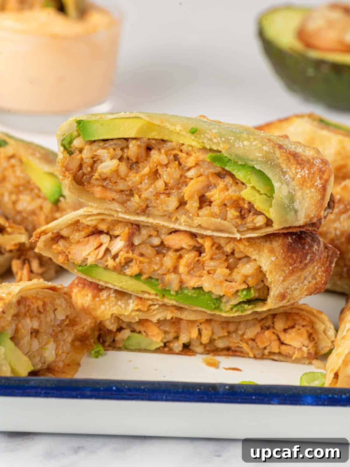 Airfried Egg Rolls cut in half and stacked on a plate.