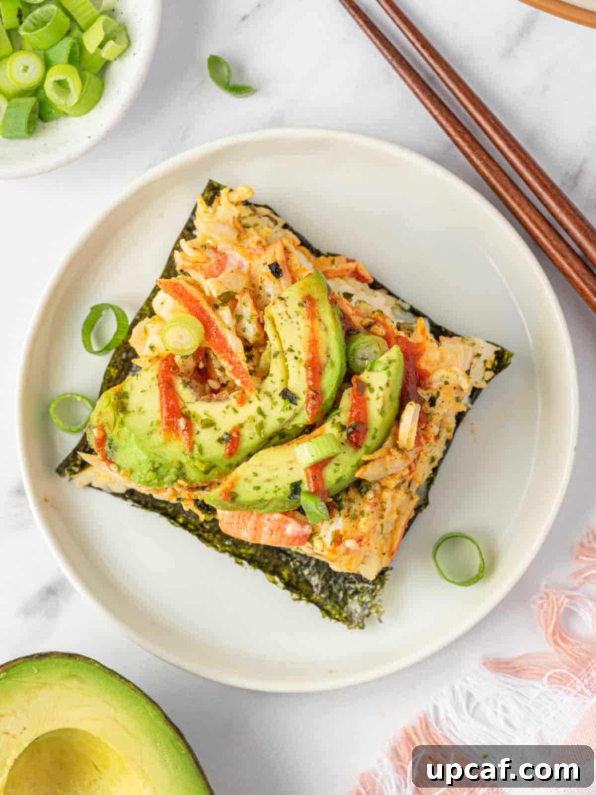 Top view of a sushi bake, with a pair of chopsticks picking up a piece.