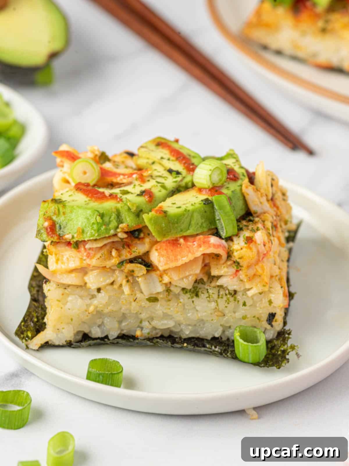A single piece of sushi bake, perfectly portioned on a nori sheet, on a white plate.