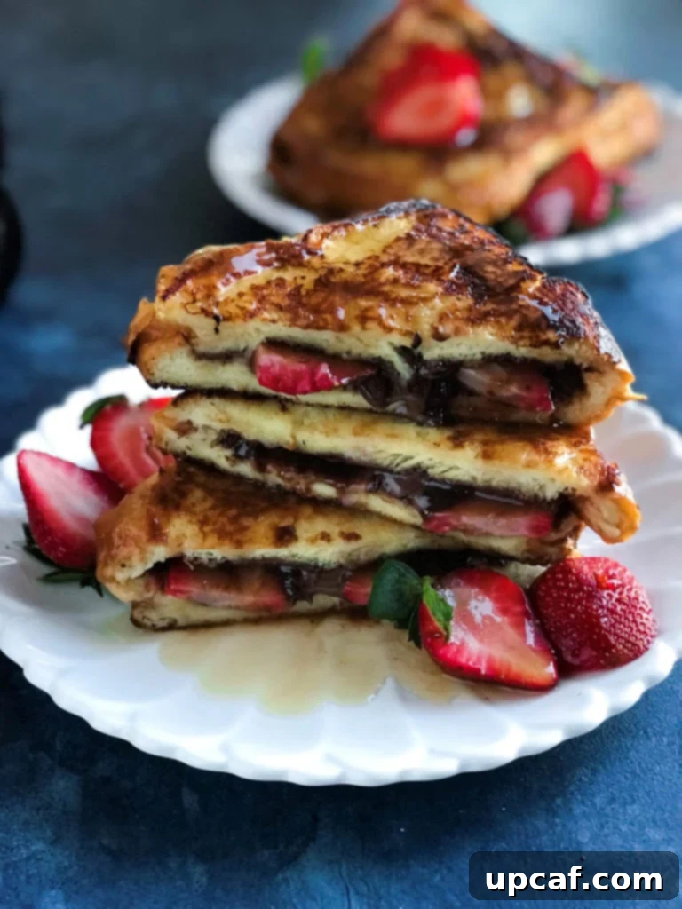 Decadent Strawberry Nutella French Toast 5 Side shot of a stack of Strawberry Nutella French Toast on a white plate, with fresh strawberries on the side.