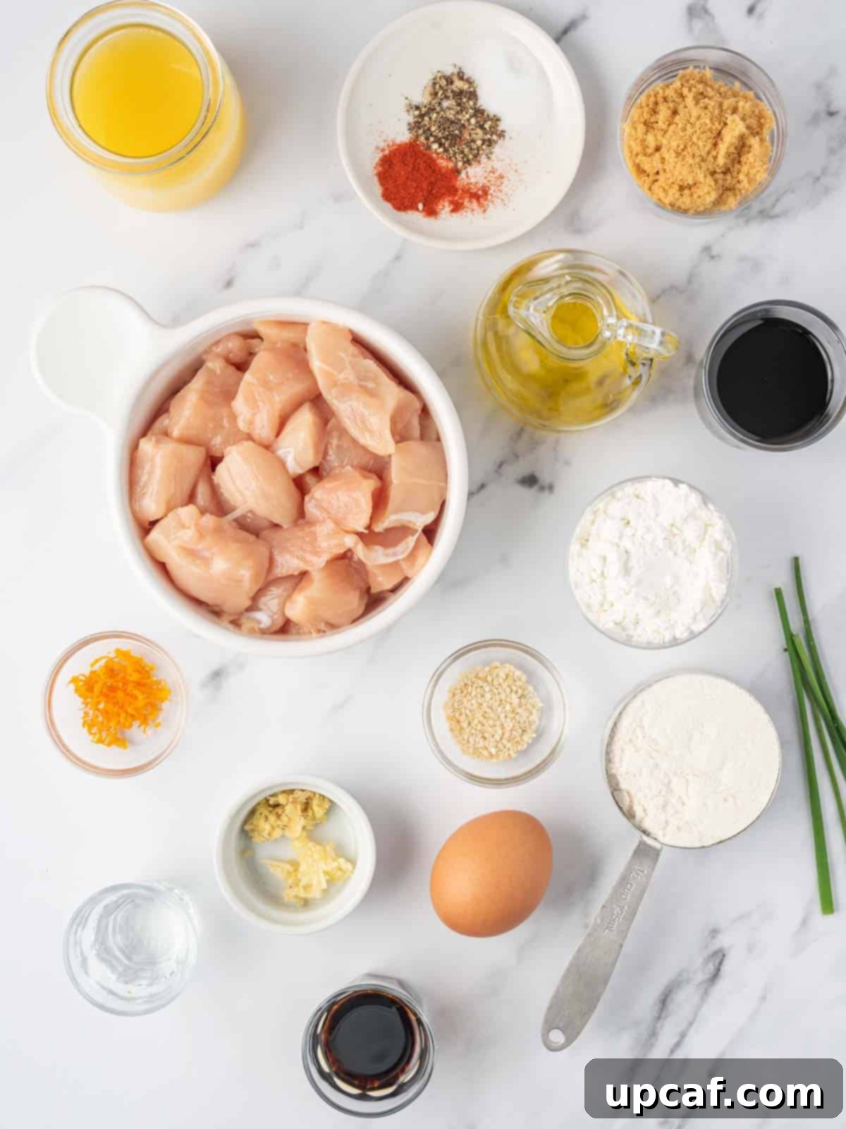 Crispy Air-Fried Orange Chicken 3 A curated display of fresh ingredients required for preparing crispy air fryer orange chicken, including chicken, oranges, soy sauce, honey, and various spices.