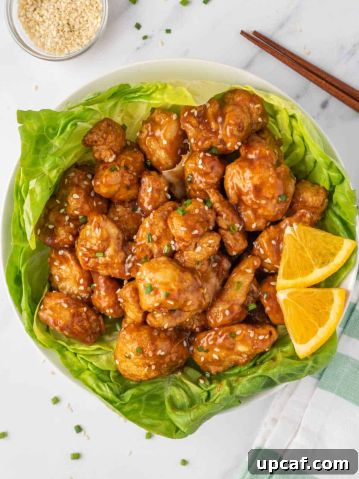 Crispy Air-Fried Orange Chicken 9 A vibrant serving of crispy air fryer orange chicken nestled on a bed of fresh green lettuce, offering a lighter presentation option.