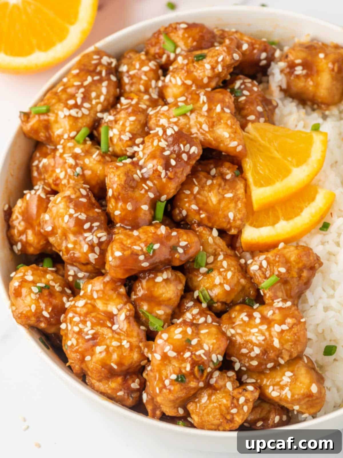 Crispy Air-Fried Orange Chicken 10 A beautifully presented bowl of crispy air fryer orange chicken alongside a generous portion of steamed white rice, highlighting a complete meal.