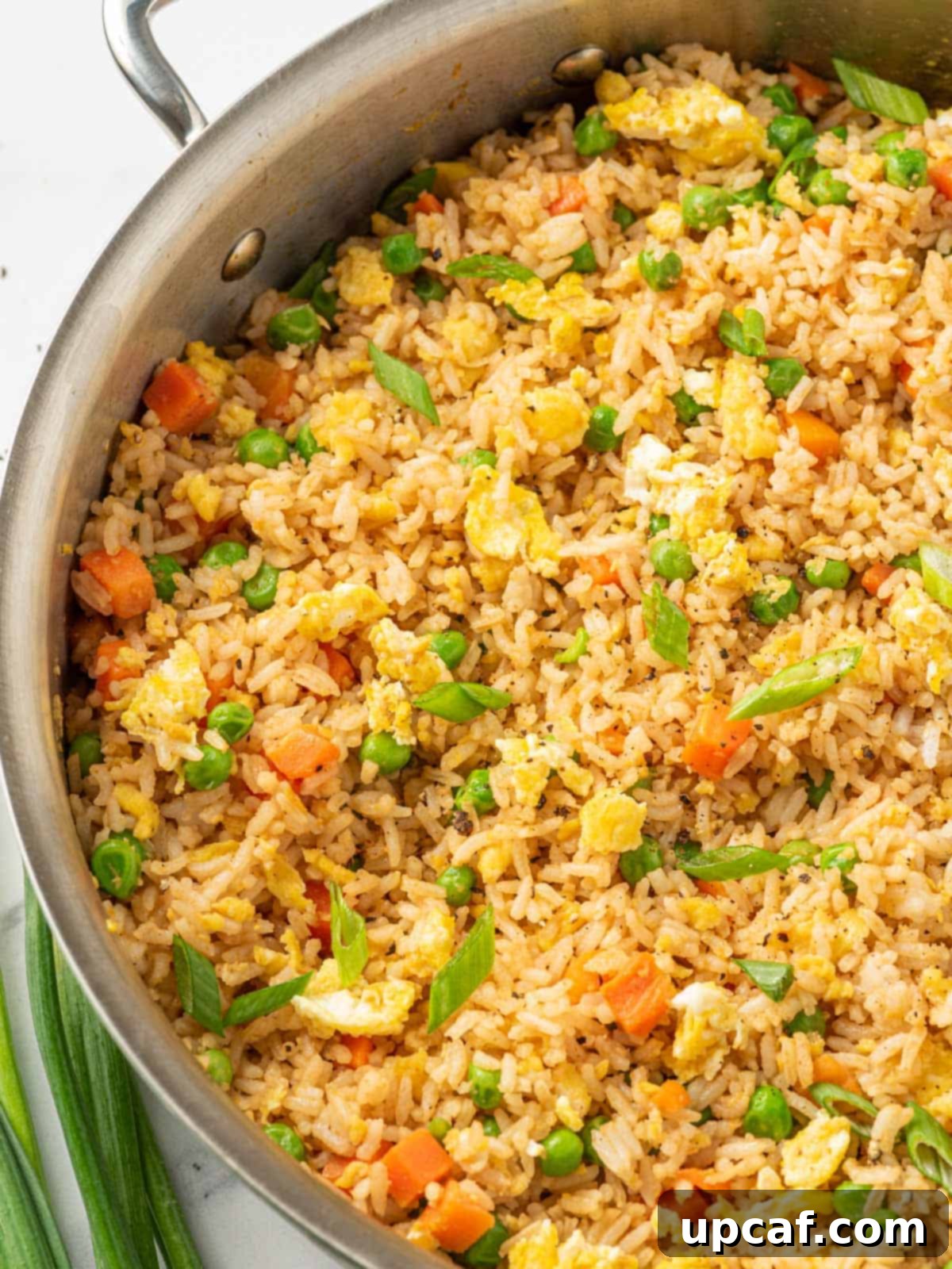 A large skillet brimming with the best Chinese fried rice, garnished and ready to serve.