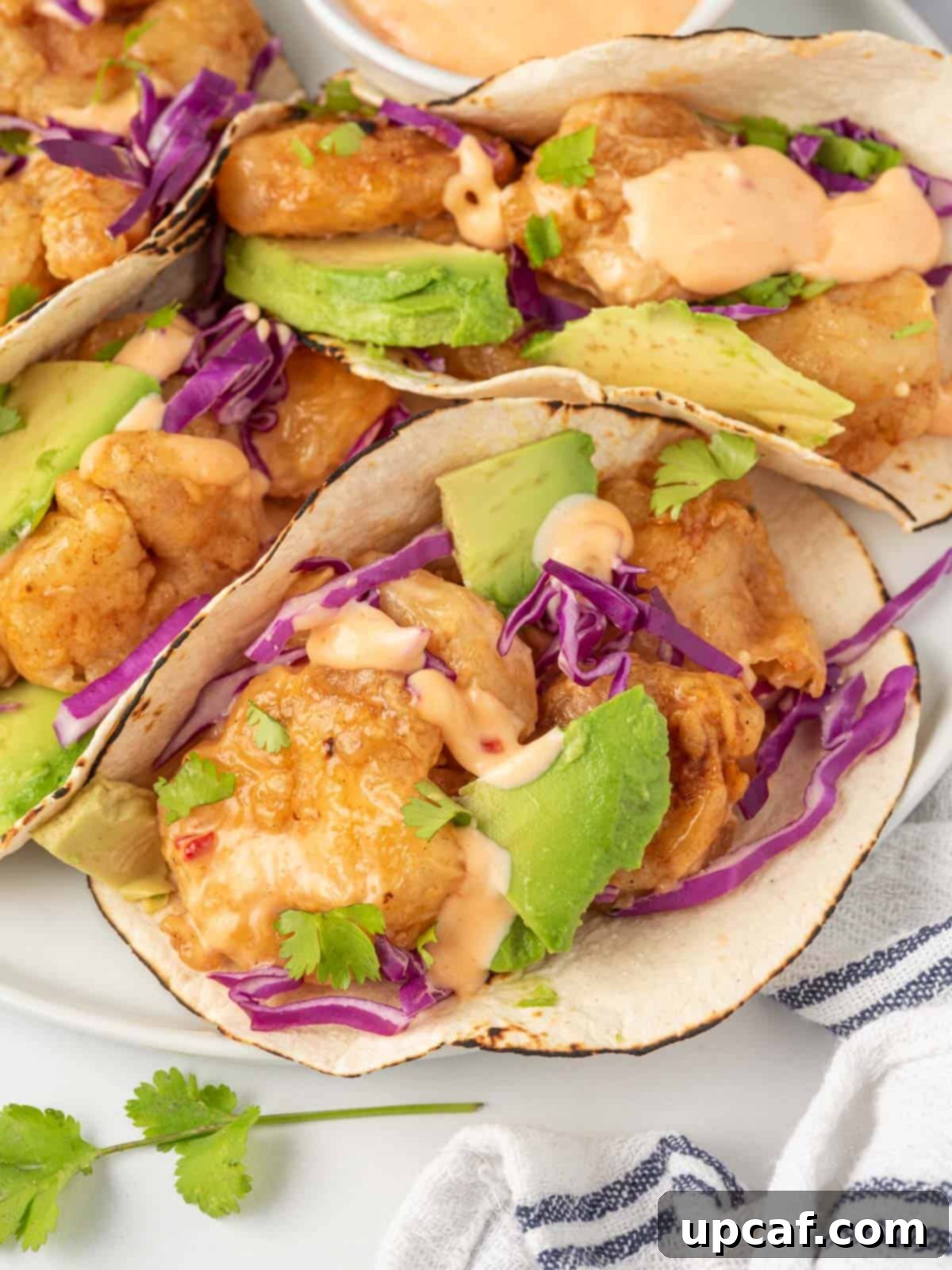 Close-up view of a bang bang shrimp taco, highlighting the crispy shrimp, sauce, and fresh toppings.