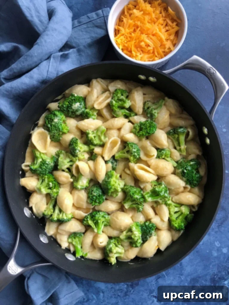 Overhead view of creamy broccoli mac and cheese pasta in a skillet, ready to serve.