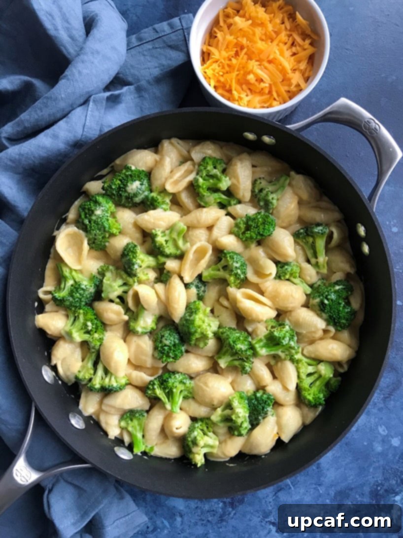 Mac and cheese in a skillet, fully mixed with broccoli, close-up.