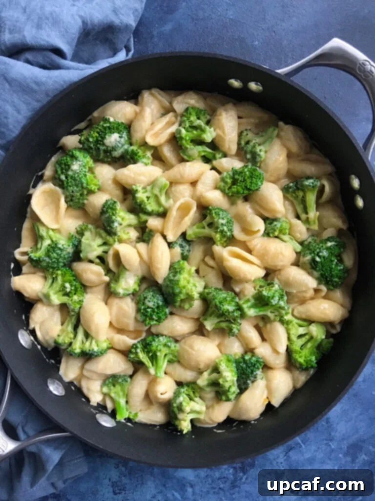 Creamy broccoli mac and cheese in a skillet, garnished with fresh parsley.